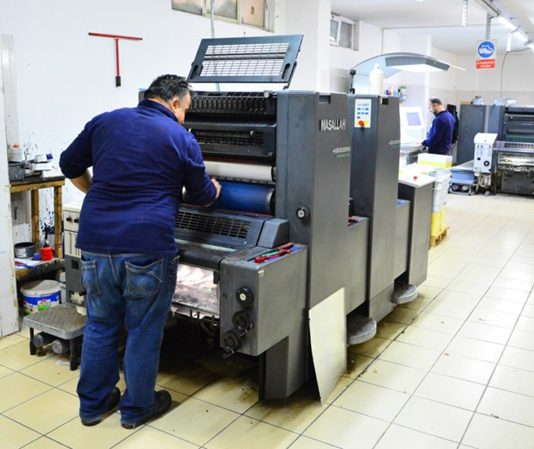 Matbaacı Kimdir? Matbaacı Ne Kadar Kazanır? Günümüzde dijitalleşmenin hız kazanmasına rağmen basılı materyallere olan ihtiyaç devam etmekte ve bu durum matbaacı mesleğinin önemini korumasını sağlamaktadır. Kitaplardan broşürlere, afişlerden kartvizitlere kadar pek çok ürünün üretiminde görev alan matbaacılar, baskı sektörünün temel taşlarından biridir. Özellikle reklam, yayıncılık ve kurumsal iletişim alanlarında matbaa hizmetleri hâlâ büyük bir yer tutmaktadır. Konulu bir haber görseli.