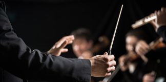 Müziğin büyülü dünyasında izleyiciyi derinden etkileyen performansların arkasında çoğu zaman görünmeyen bir lider vardır: orkestra şefi. Sahnenin önünde, elindeki baton ile onlarca müzisyeni yöneten bu kişi, yalnızca ritim tutan biri değil, aynı zamanda müziğin ruhunu şekillendiren bir sanatçıdır. Klasik müzikten film müziklerine kadar geniş bir alanda görev alan orkestra şefi, sanat ve disiplinin birleştiği özel bir mesleği temsil eder. Konulu bir haber görseli.