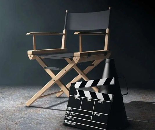 Yönetmen Kimdir? Yönetmen Ne Kadar Kazanır? Yönetmen, sinema, televizyon, tiyatro ya da dijital platformlar için hazırlanan projelerin tüm yaratıcı sürecini yöneten kişidir. Bir yapımın ortaya çıkışından izleyiciyle buluşmasına kadar geçen süreçte en kritik rolü üstlenen Yönetmen, projenin hem sanatsal hem de teknik boyutunu kontrol eder. Bu nedenle yönetmenlik, yalnızca teknik bilgi değil aynı zamanda güçlü bir vizyon ve liderlik gerektiren bir meslek olarak öne çıkar. Konulu bir haber görseli.